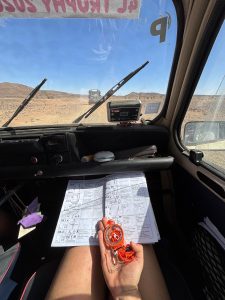 Un journal de bord et une boussole dans une 4L trophy en plein désert